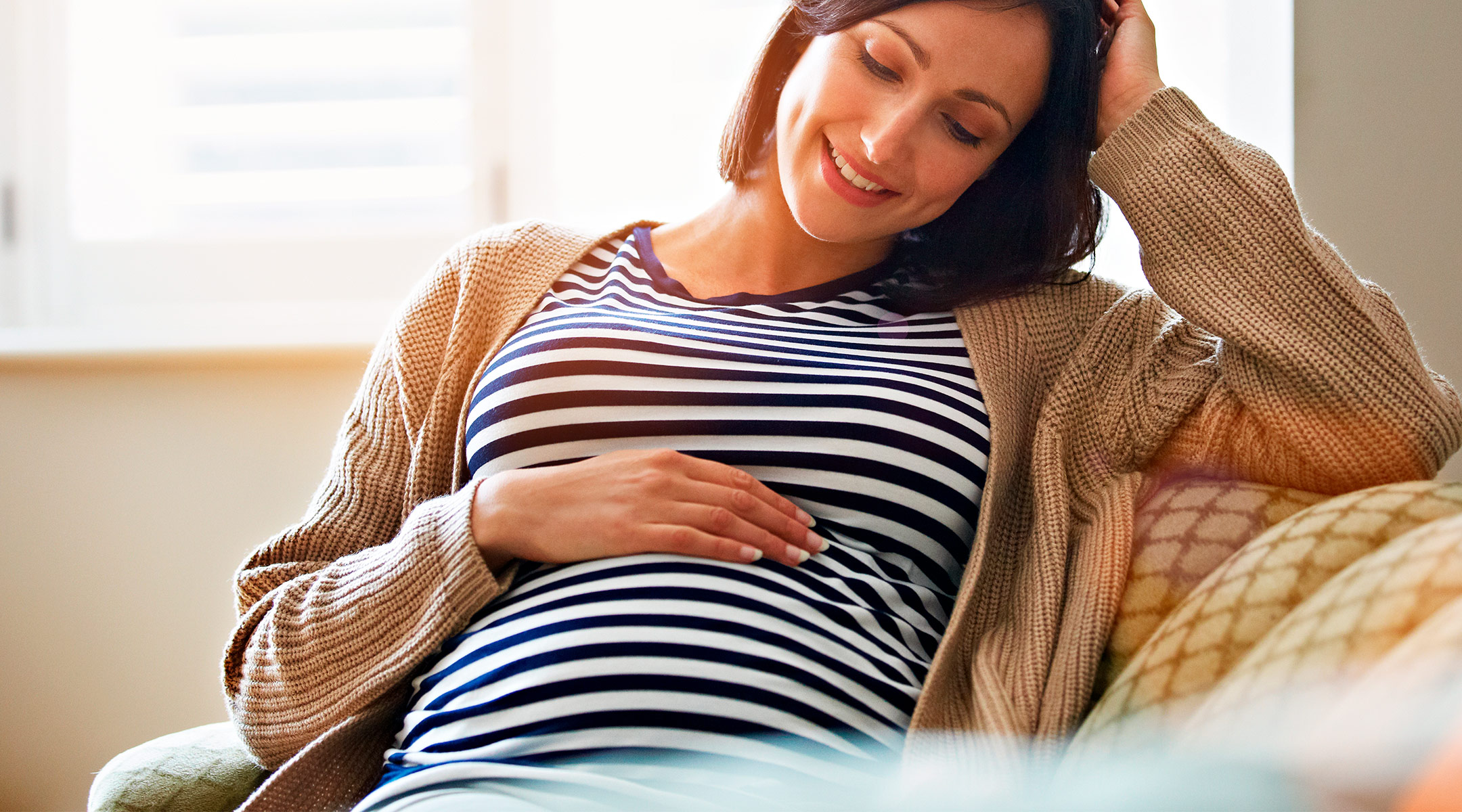 pregnant woman smiling and touching her belly. 
