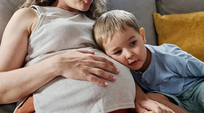 young boy resting his head on his mother's pregnant belly