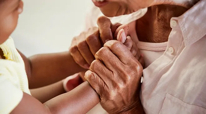 grandmother and baby holding hands looking at each other