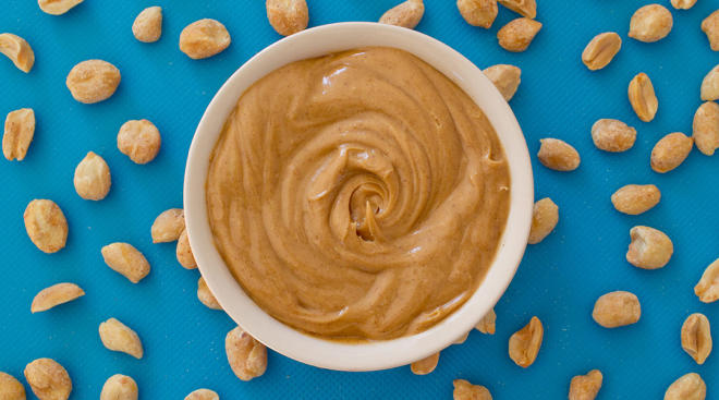 peanut butter in dish surrounded by peanuts