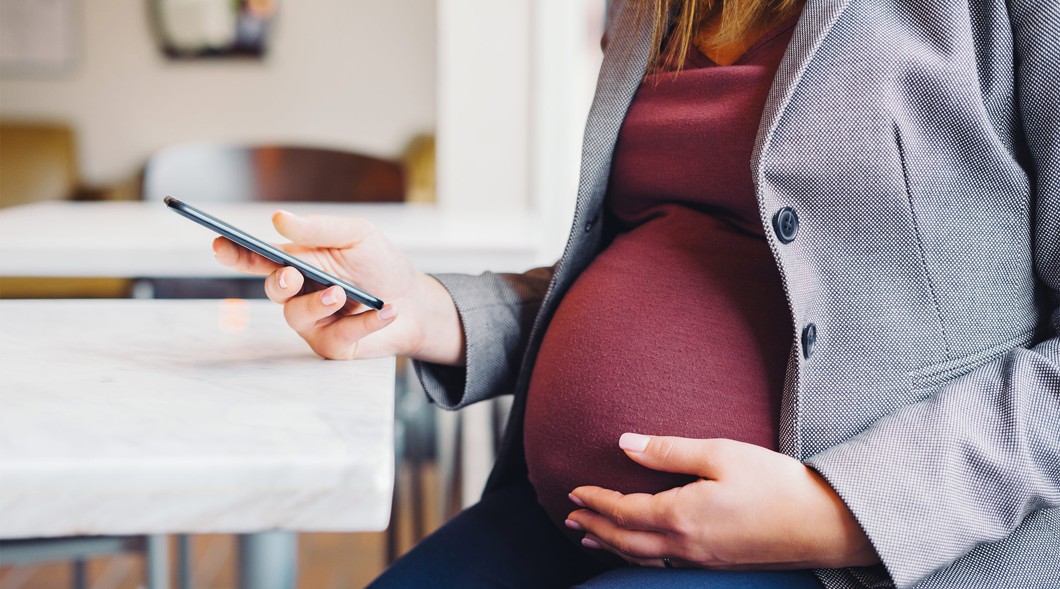 pregnant woman looks at her phone