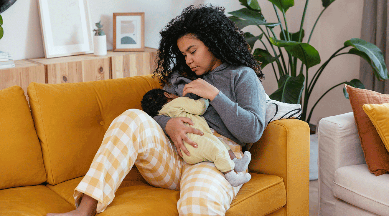 mother breastfeeding baby at home on the couch