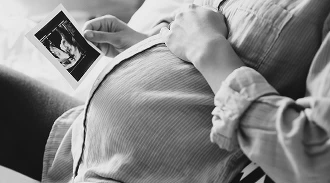 close up of pregnant woman holding a picture of her ultrasound