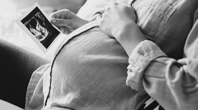 close up of pregnant woman holding a picture of her ultrasound