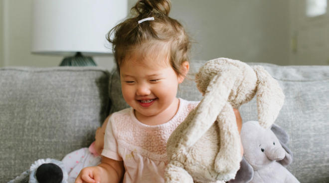 happy toddler playing with stuffed animal bunny