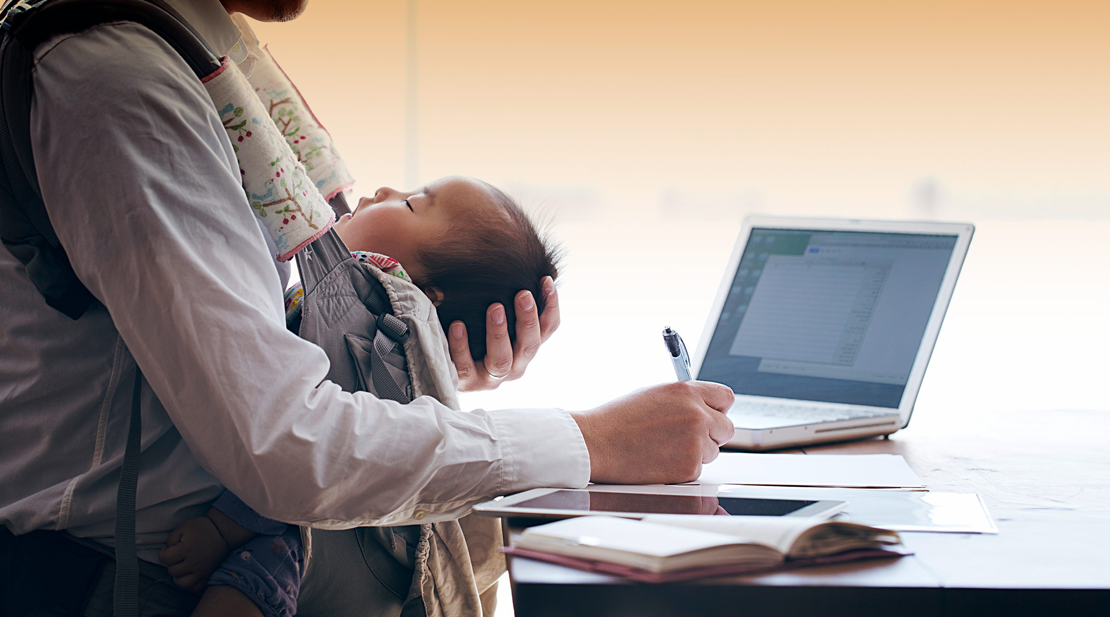 dad working with baby in baby carrier at home 