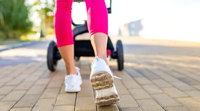 close up of woman's feet walking while pushing stroller outside on a sunny day