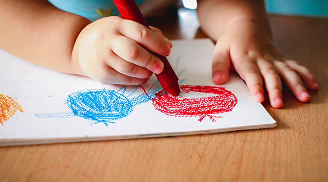 child coloring with crayons on paper