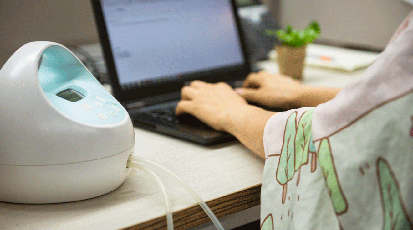 mother using breast pump while working on computer in office