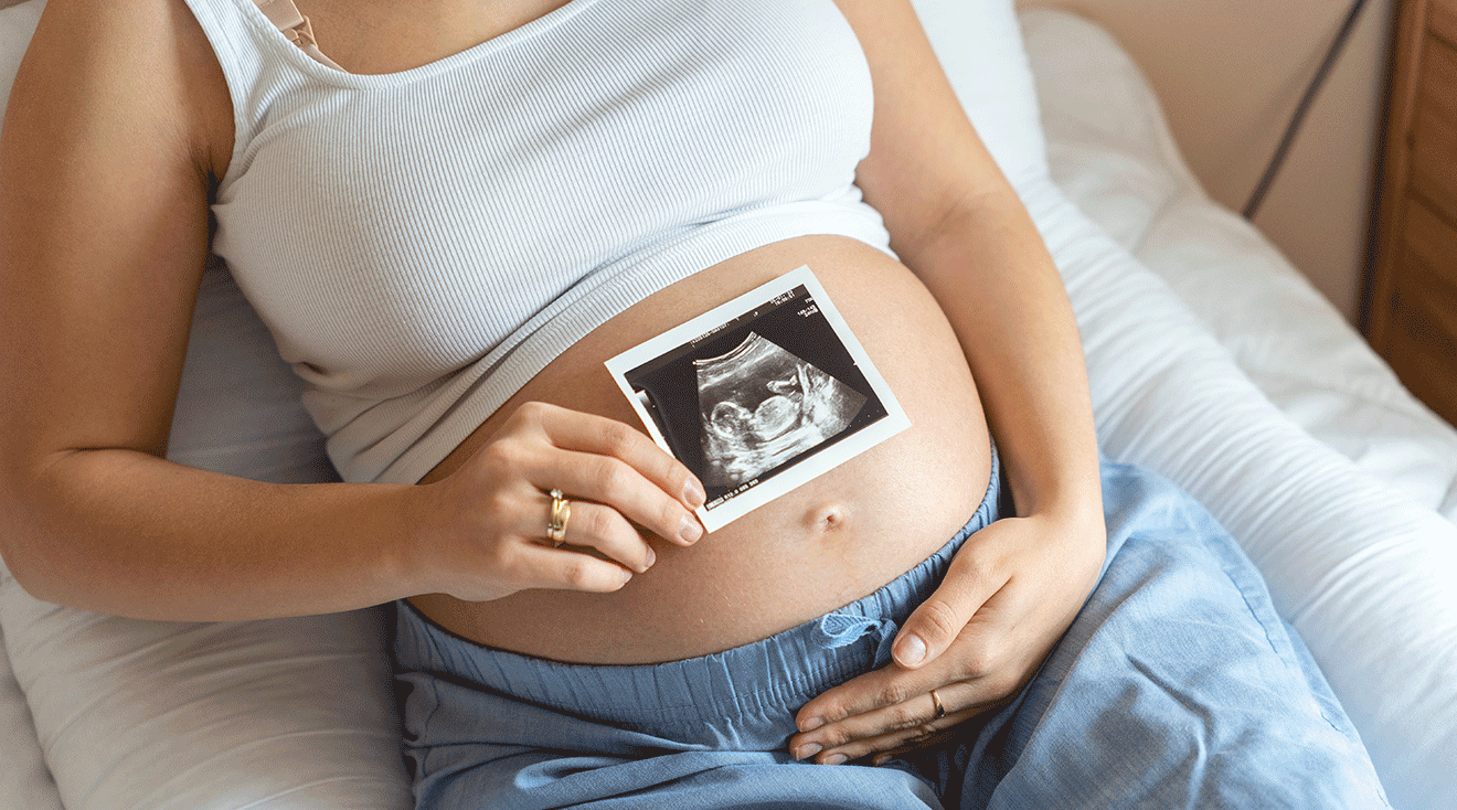 pregnant woman holding ultrasound photo over belly