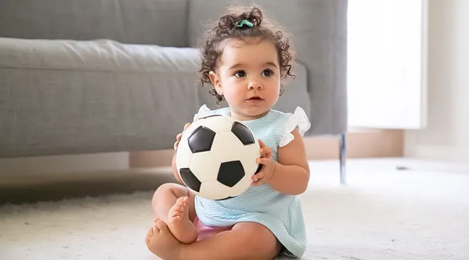 baby playing with a soccer ball at home