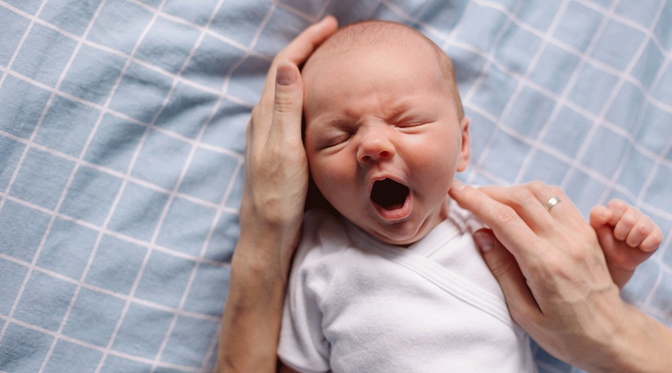 infant yawning in mom's arms