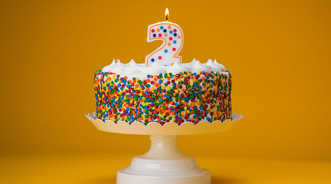 birthday cake with rainbow sprinkles and a number 2 candle