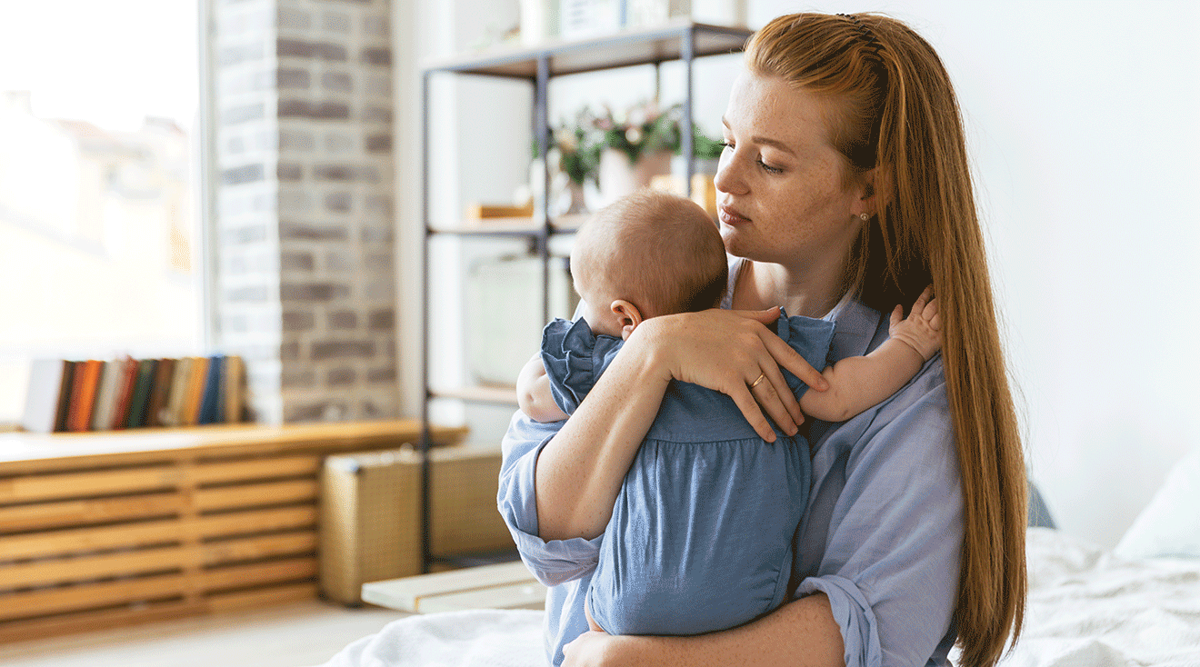 depressed mother holding newborn baby at home