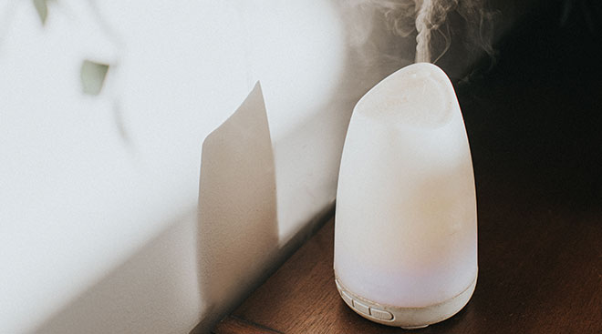 white essential oil diffuser on wood table