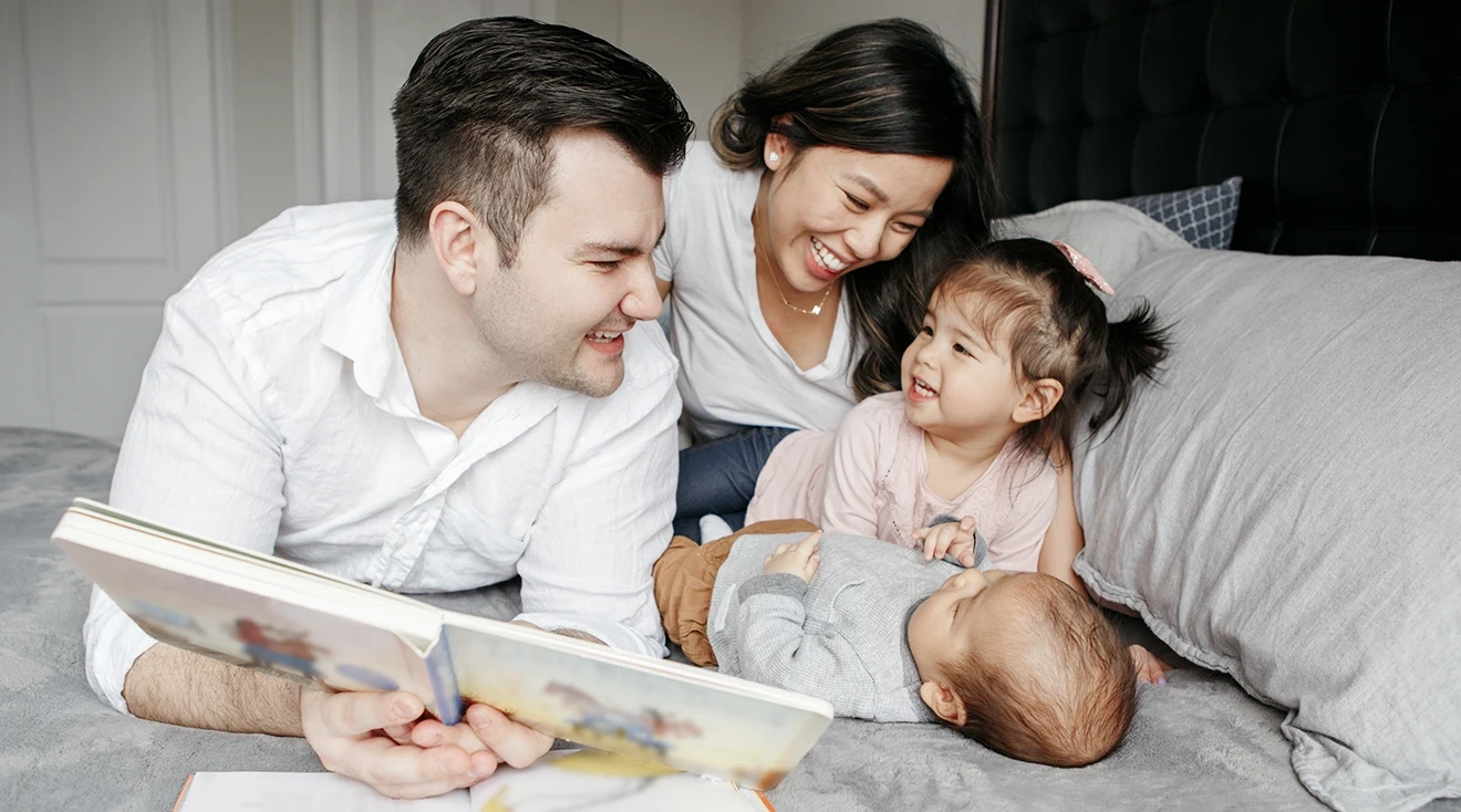 family reading baby books in bed 