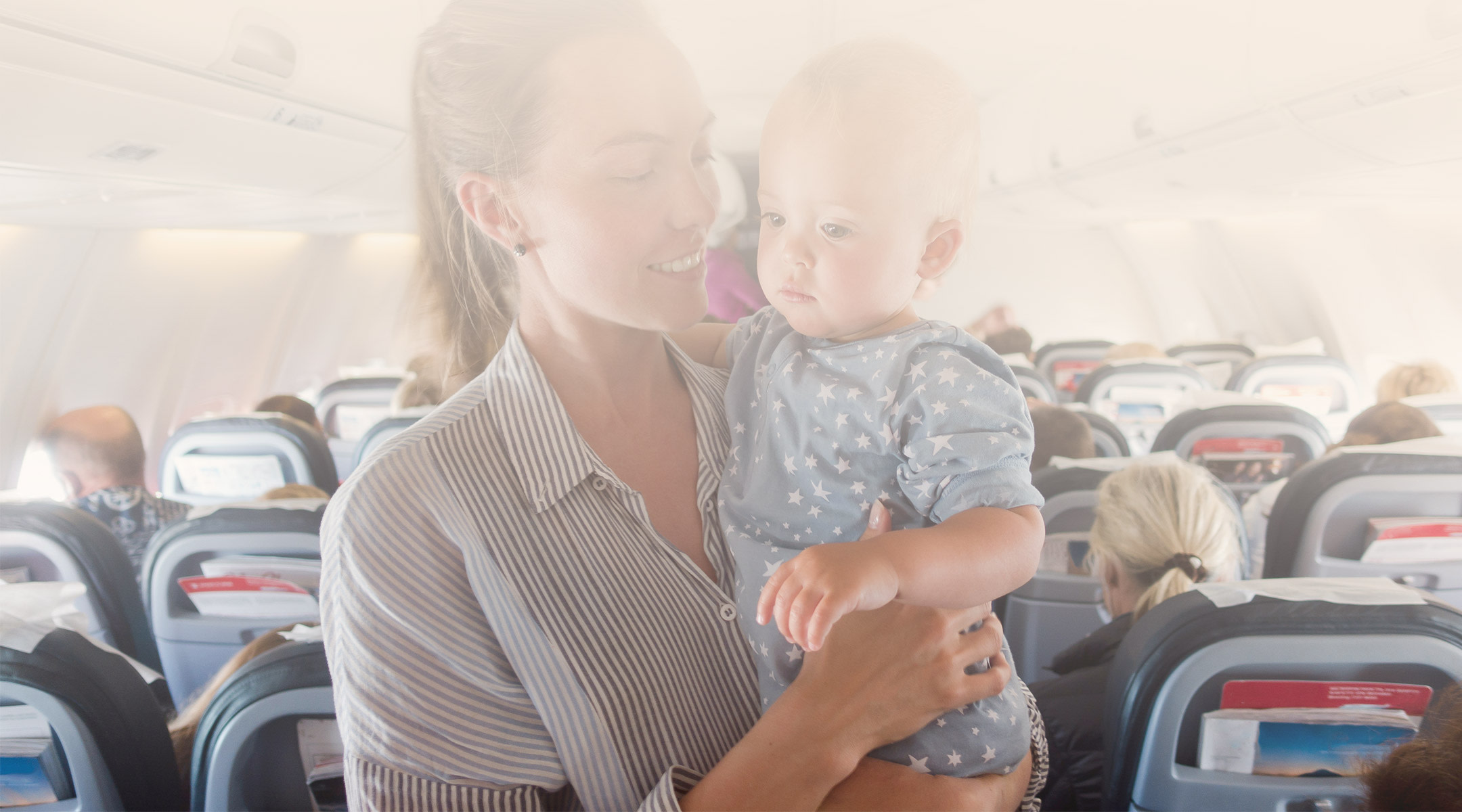mom holds upset baby on airplane flight