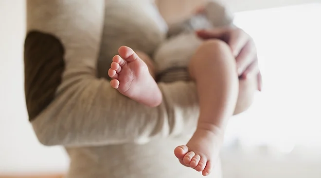 close up of baby's feet while unrecognizable person holds baby