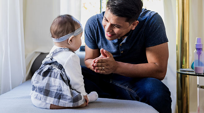 Dad smiling and looking at his baby daughter.