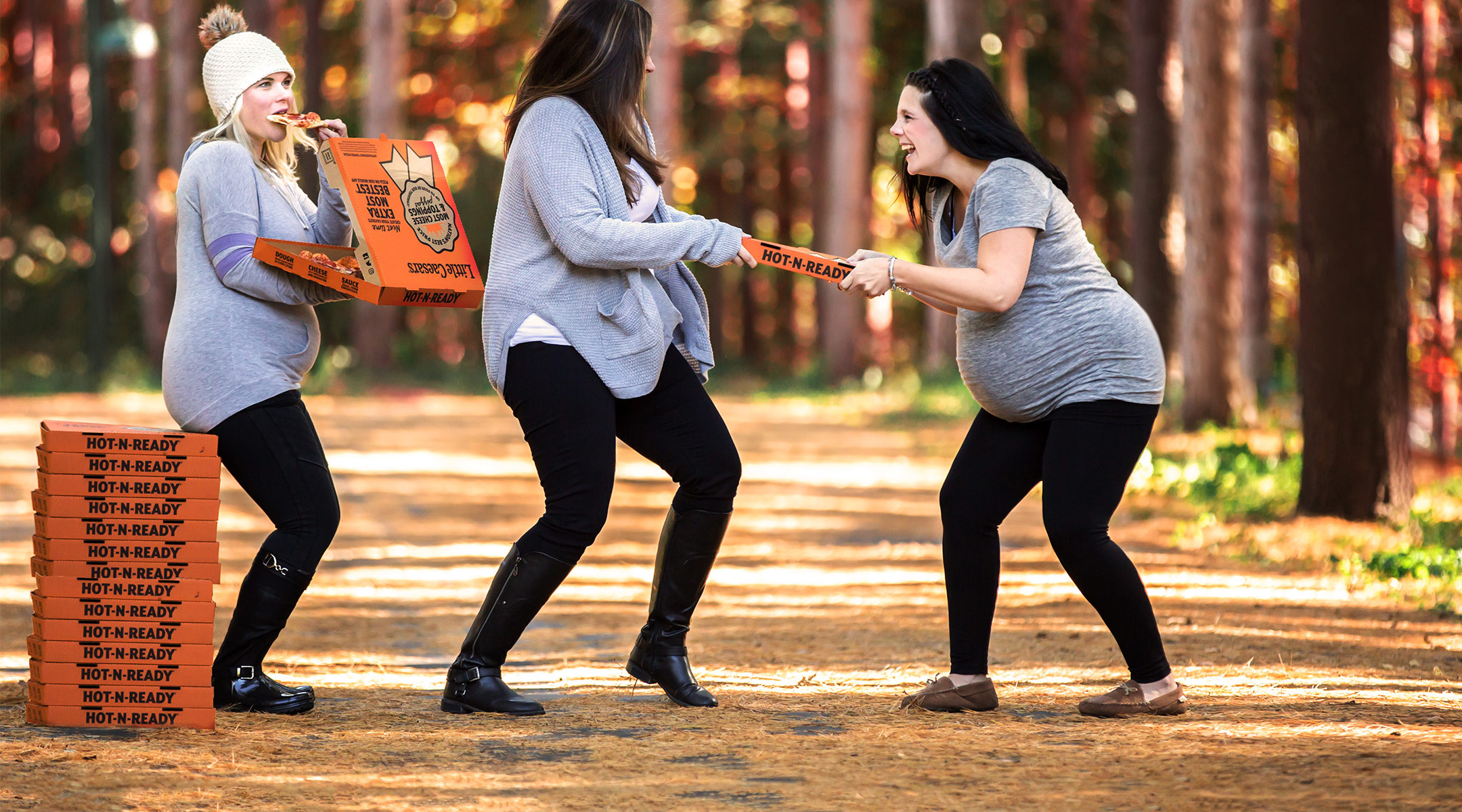 funny photo shoot of pregnant women enjoying and fighting over pizza