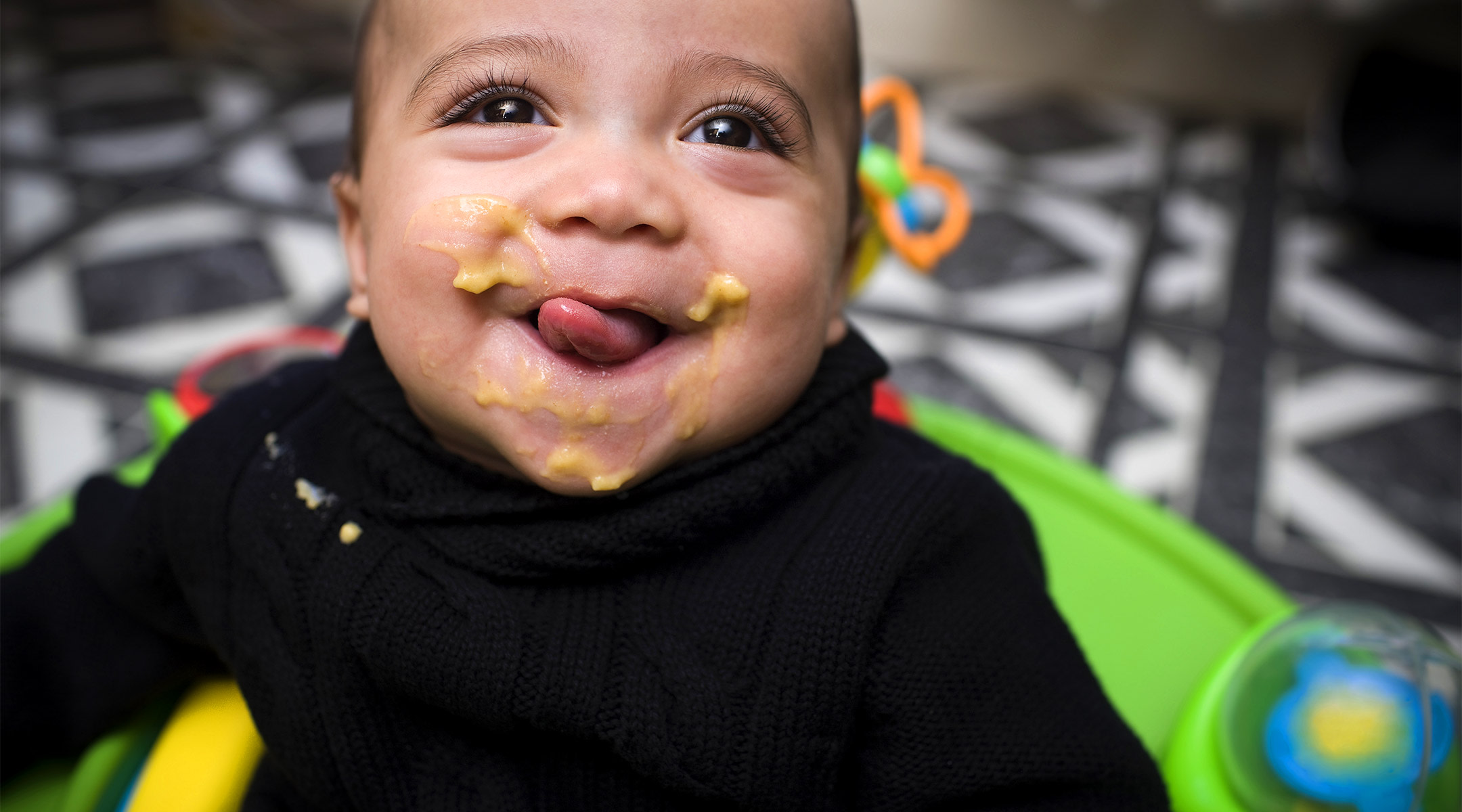 happy baby smiling and eating solid food