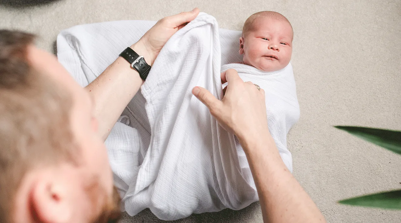 dad swaddling baby at home