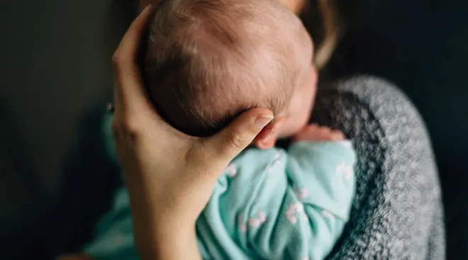 close up of mother holding the back of newborn baby's head