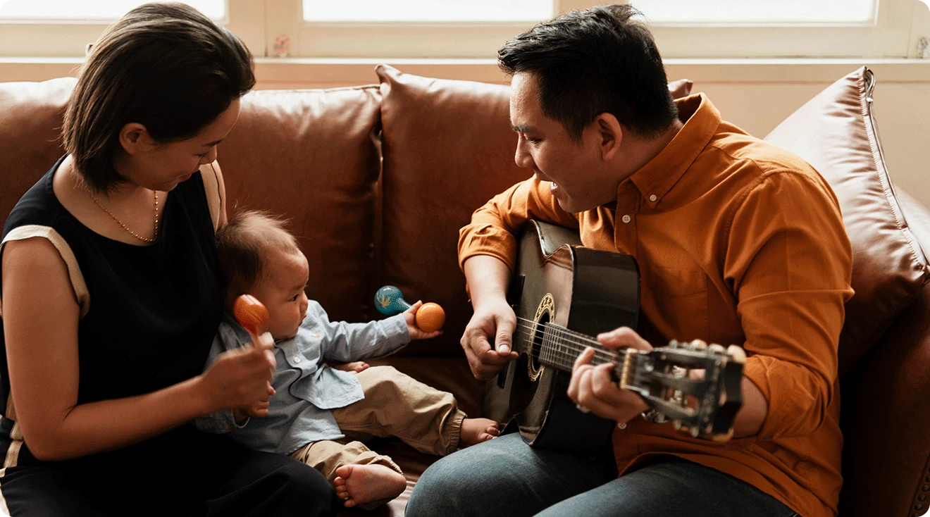 mom and dad singing to baby with guitar