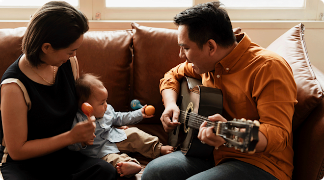 mom and dad singing to baby with guitar