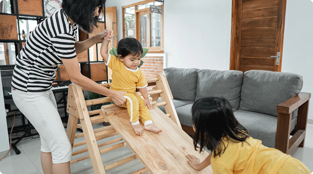 mom helping toddlers play on pikler triangle at home