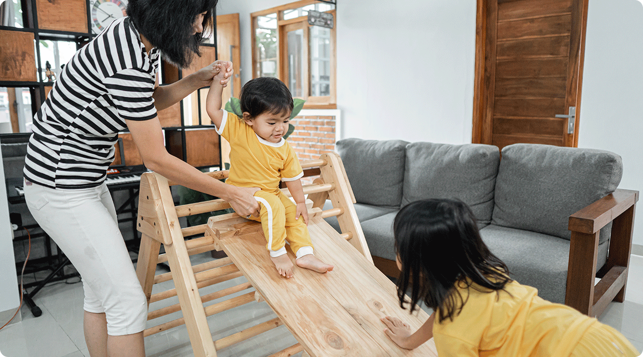 mom helping toddlers play on pikler triangle at home