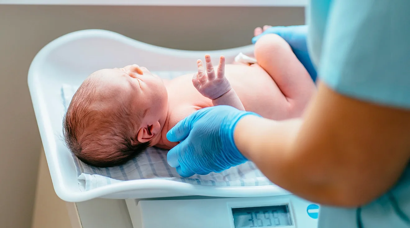 newborn baby on scale at hospital after birth