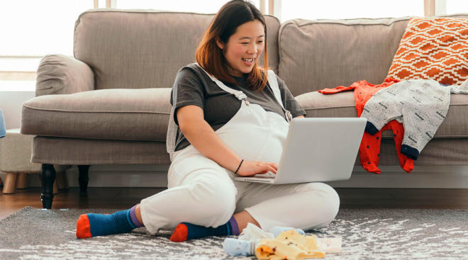 very pregnant woman looking at her laptop