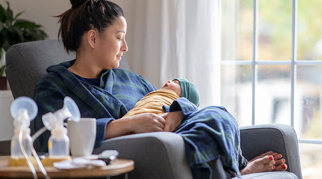 Mom soothing newborn baby with her breastfeeding pump nearby. 