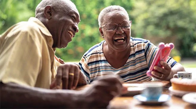 grandparents laughing while eating meal and looking at their phone
