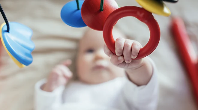 baby grabbing toy while lying down 