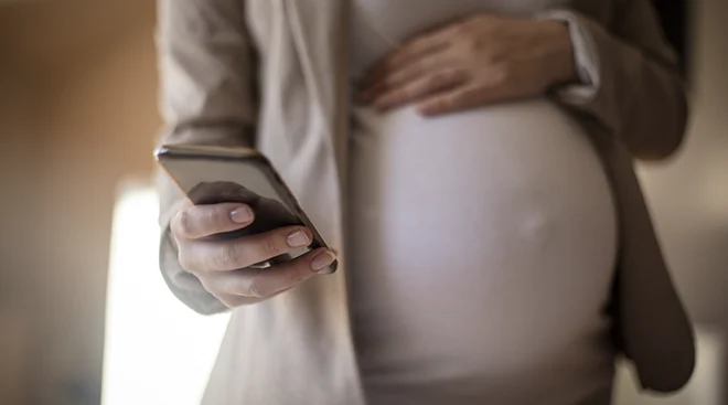 close up of pregnant woman holding smartphone in hand