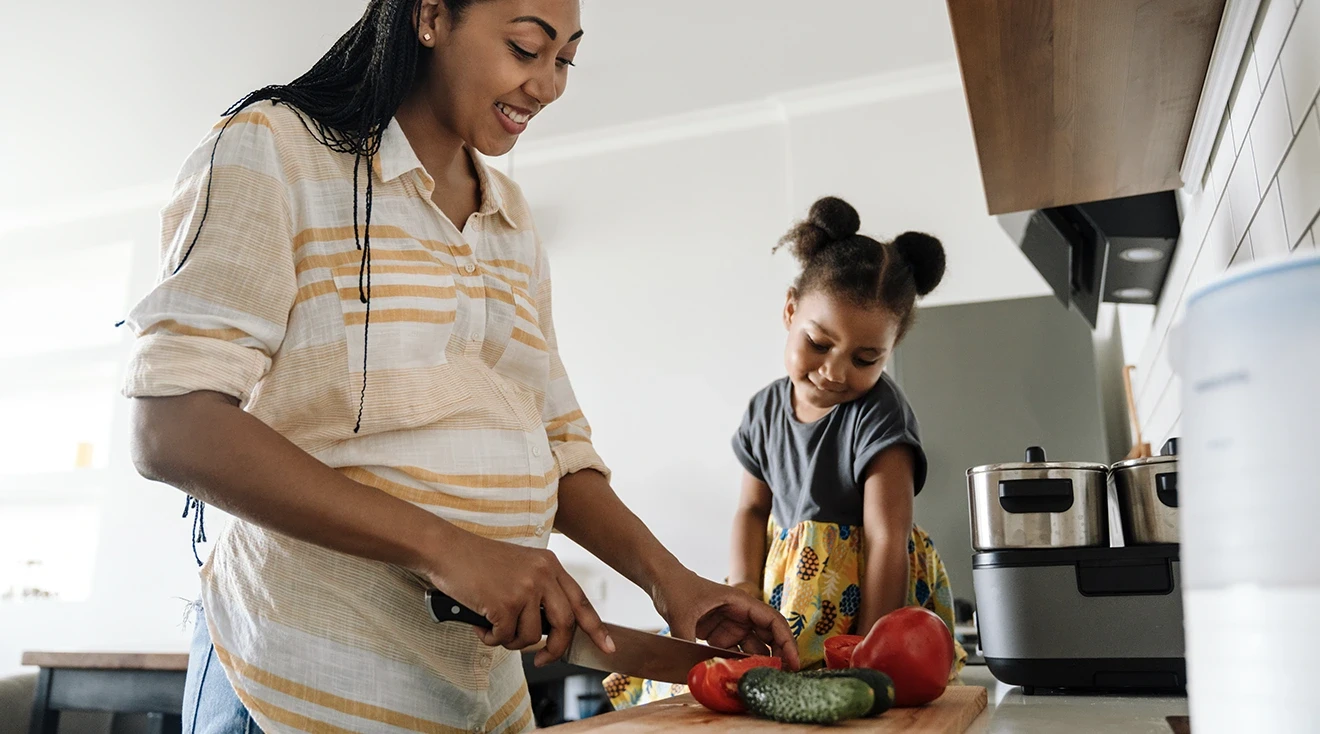 pregnant woman preparing healthy food with toddler in kitchen