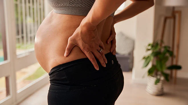 close up of pregnant woman with hands on lower back