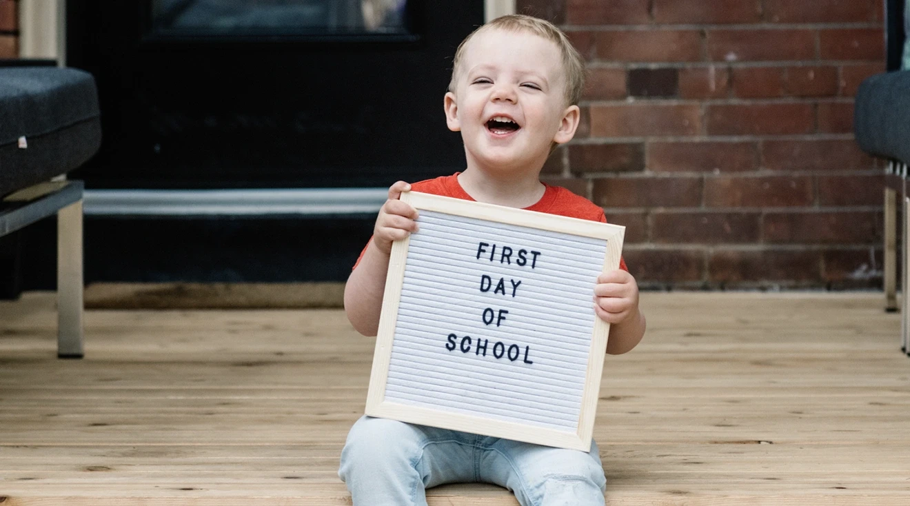 toddler holding a sign that says "first day of school"