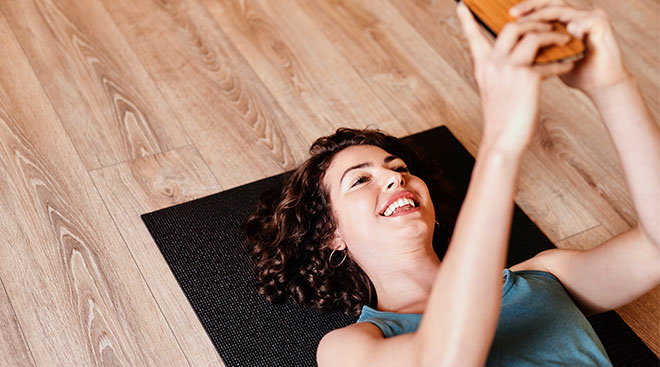 Woman laughing and getting ready to exercise while looking at her phone. 