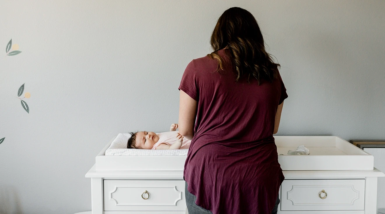 mother using changing table to change baby's diaper