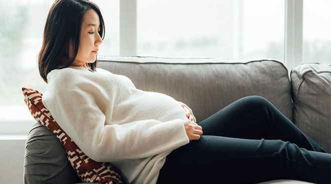 Contemplative pregnant woman looking at her belly. 