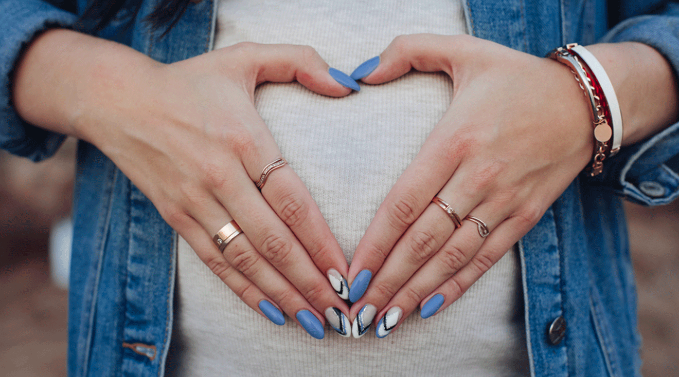 close up of pregnant woman's hands with manicure on belly