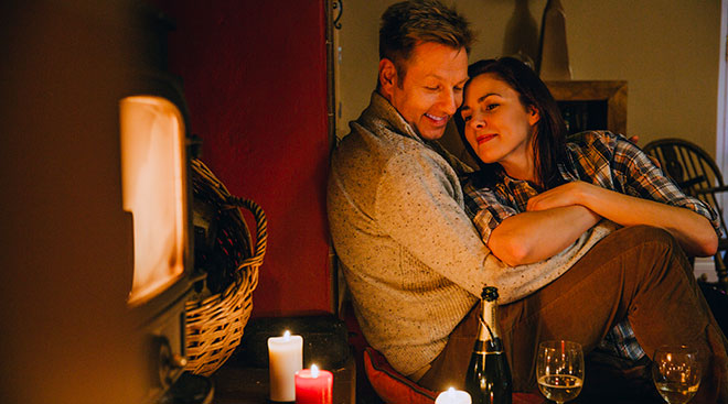 young couple at home enjoying a romantic date night with wine and candles