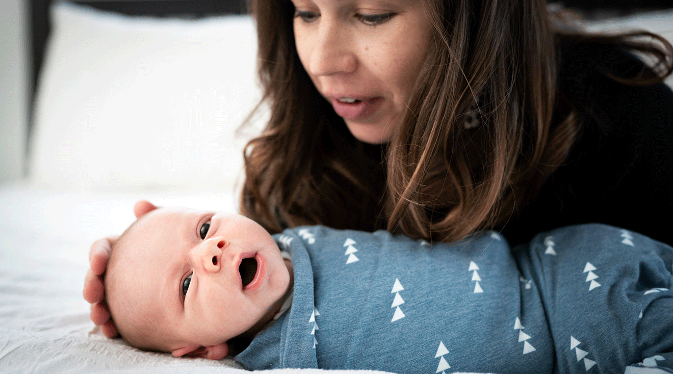 mom and newborn baby on bed at home