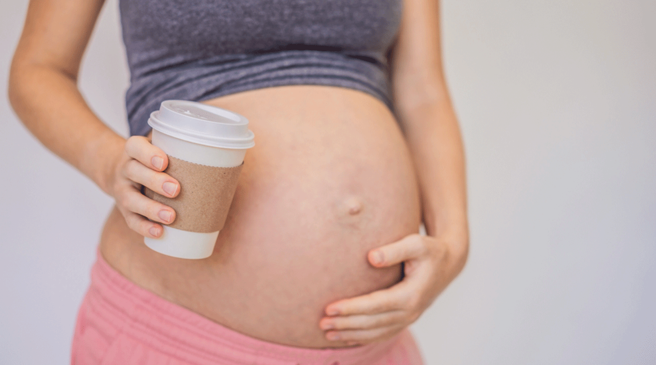 pregnant woman holding to go coffee cup