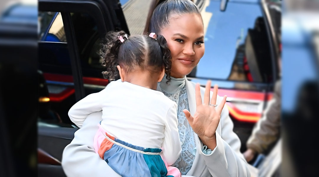 chrissy teigen holding her daughter, who is hiding her face