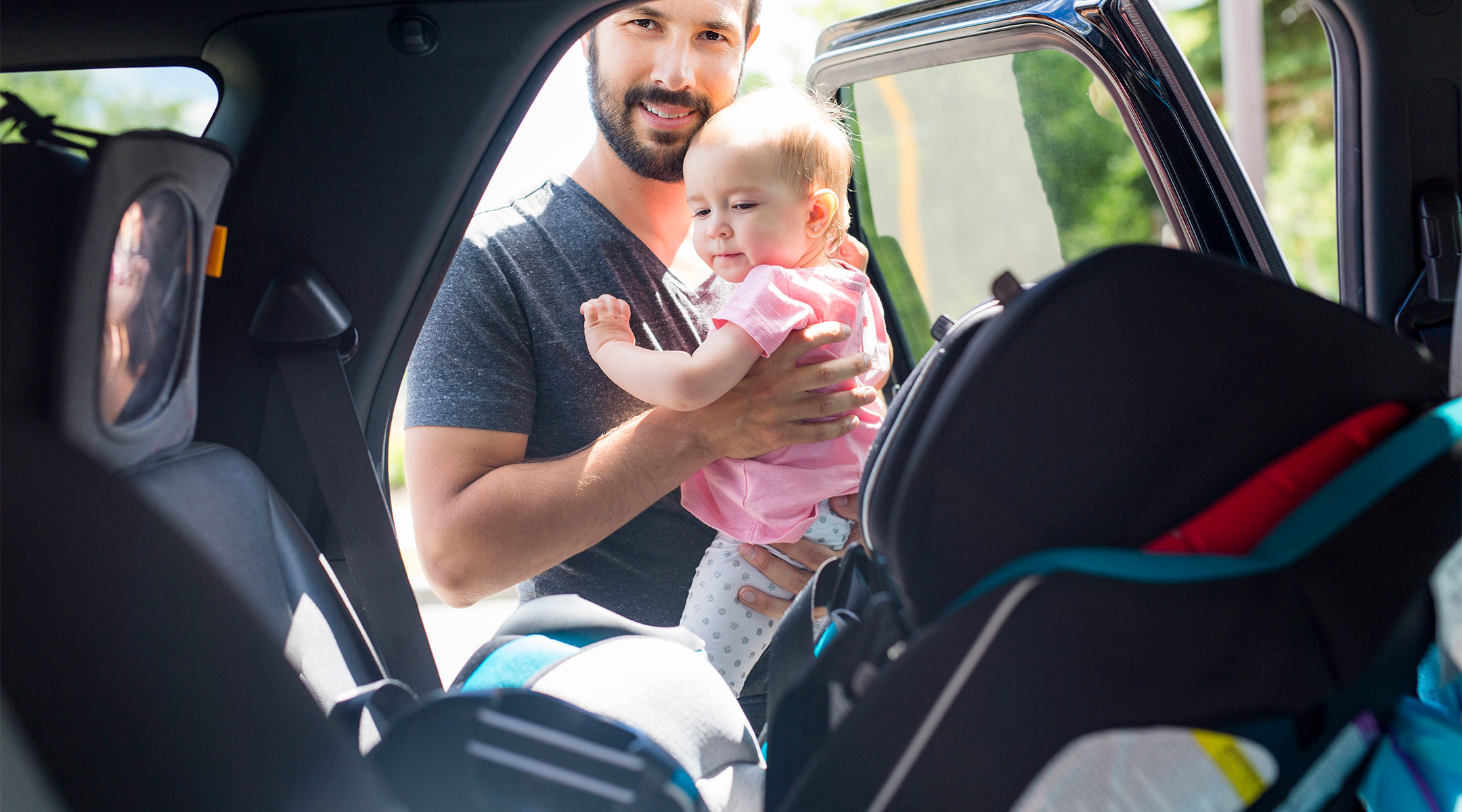 dad safely straps baby into car seat preventing injury from a crash