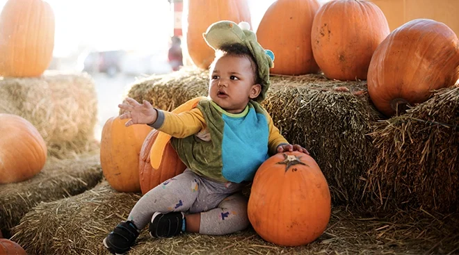 baby dressed in dinosaur halloween costume at the pumpkin patch